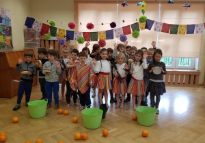 Dzieci przebrane pozują na tle koszy i pomarańczy